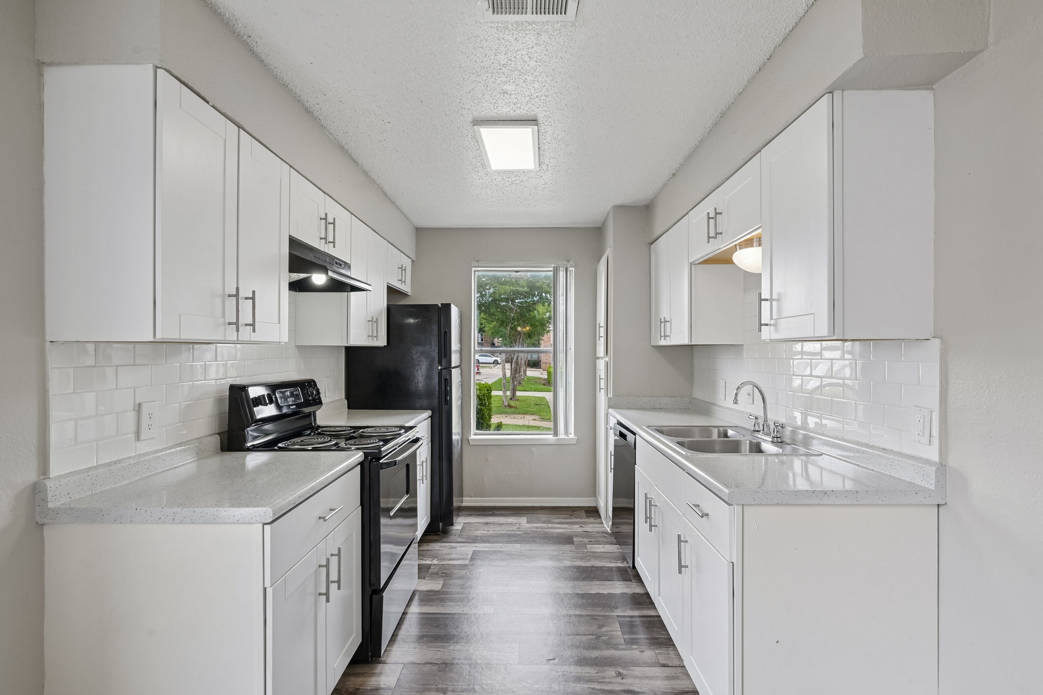 A kitchen with white cabinets and black appliances.
